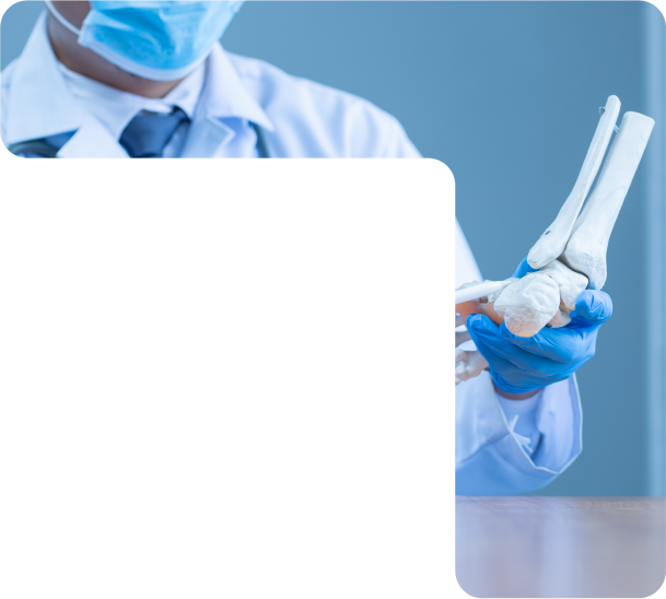 An orthopedic doctor in a mask holds a skeletal model of a human foot and ankle to explain a medical condition.